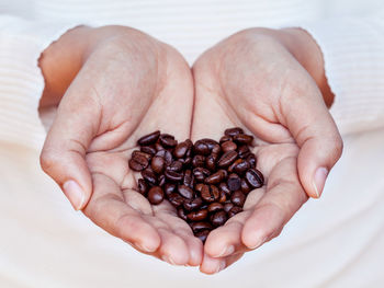 Close-up of human hands holding roasted coffee beans