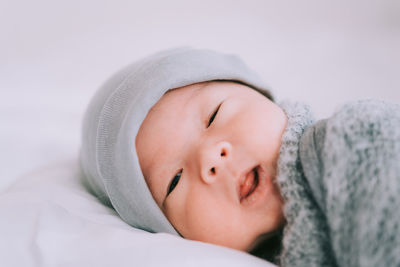 Close-up of cute baby boy lying on bed