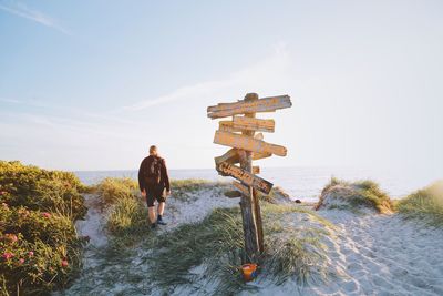 Rear view of man walking on sand against sky