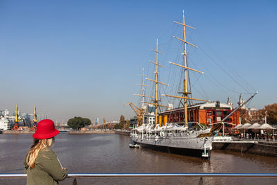 Rear view of man sailing on river against clear sky