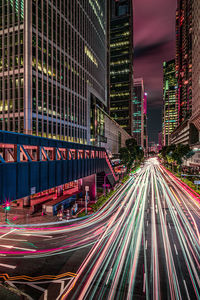 Light trails on city street by buildings at night