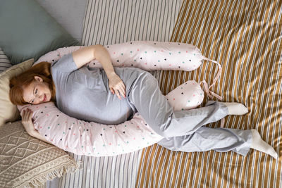 Directly above shot of pregnant woman lying on bed at home