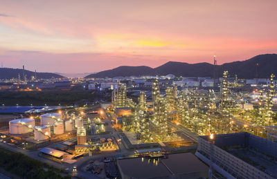 Aerial view of illuminated refinery against sky at sunset