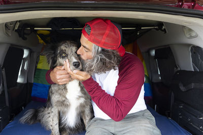 Gay man sitting inside a van with his black pet dog enjoying the sunny day. person