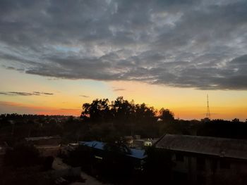 High angle view of silhouette trees and buildings against sky at sunset