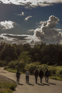 Rear view of people walking on road against sky