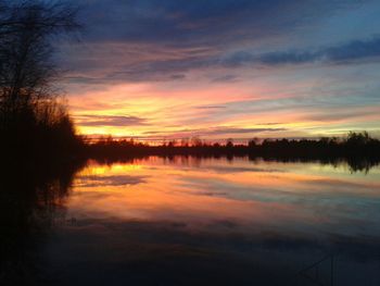 Reflection of trees in lake at sunset