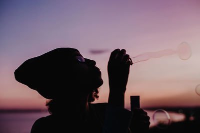 Silhouette woman standing against sky during sunset