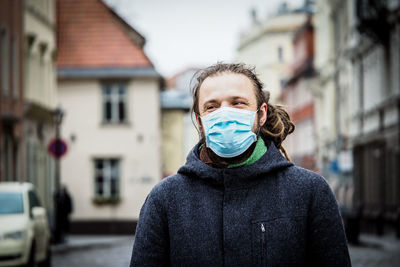 Smiling man wearing mask looking away while standing on road