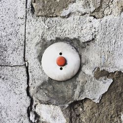 Close-up of red push button on damaged wall