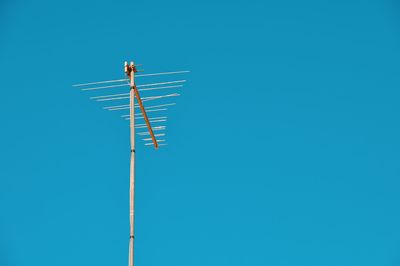 Low angle view of telephone pole against clear blue sky