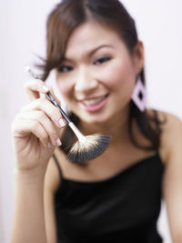 Portrait of smiling woman holding make-up brush at home