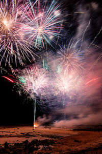 Firework display at beach during night