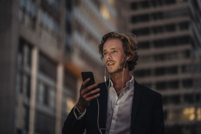 Businessman in the city at dusk using cell phone