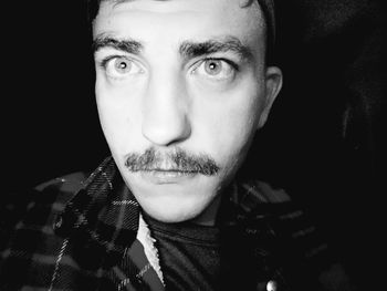 Close-up portrait of young man against black background