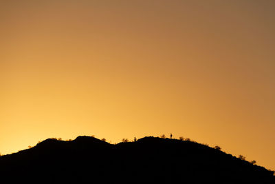 Silhouette mountain against orange sky