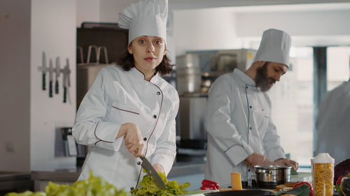 Portrait of female trainee cutting vegetable in kitchen