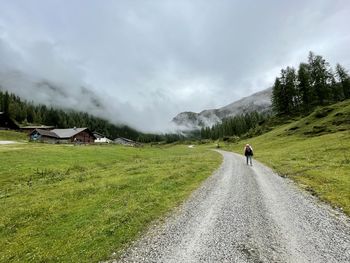 Rear view of man walking on road against sky