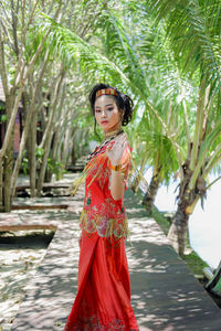 Portrait of young woman standing against plants