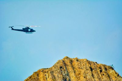 Low angle view of helicopter flying against clear blue sky