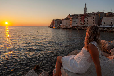 Rear view of woman looking at sea during sunset