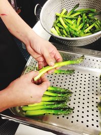 High angle view of woman holding asparagus while standing in kitchen