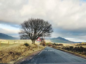 Road amidst bare trees against sky