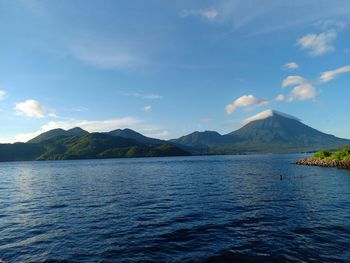 Scenic view of lake by mountains against sky