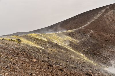 Sulphur gas on arid landscape against clear sky