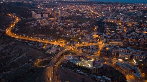 High angle view of illuminated street amidst buildings in city at night