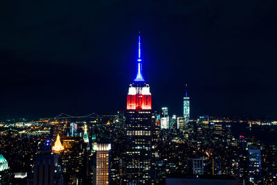 Illuminated empire state building and cityscape against clear sky at night