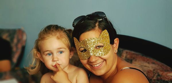 Portrait of smiling woman with daughter against wall