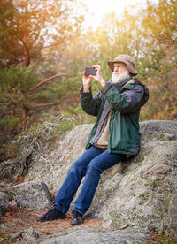 Man photographing with mobile phone in forest