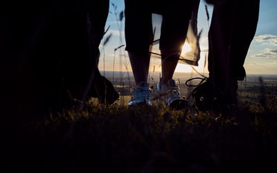 Low section of people walking on plants at sunset