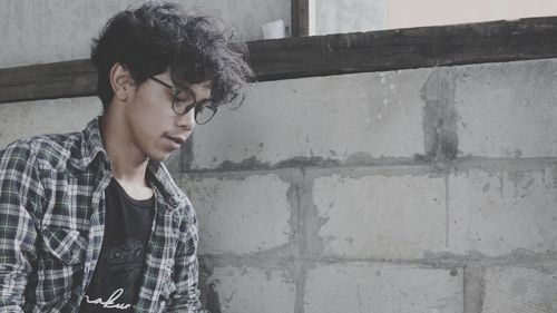 Portrait of young man looking away against wall