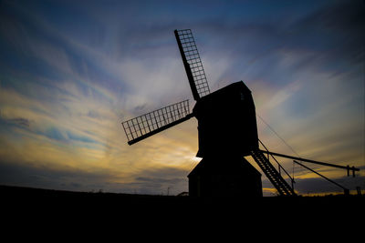 Low angle view of silhouette windmill on field against sky