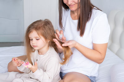 Midsection of mother taking care of daughters hair