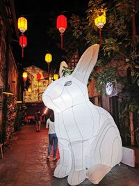 Illuminated lanterns hanging amidst buildings in city at night