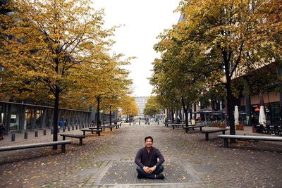 Portrait of man sitting on footpath in city