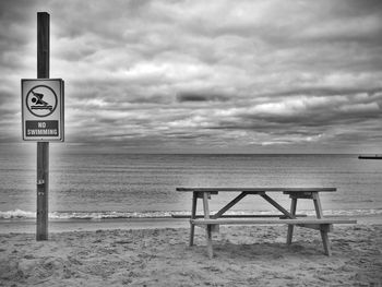 Information sign on beach against sky