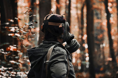 Rear view of man standing against trees in forest