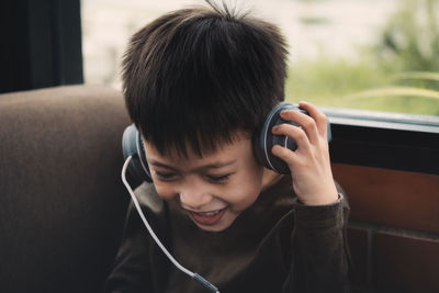 Cute smiling boy listening music on headphones at home
