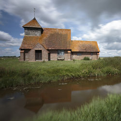 Old building by lake against sky