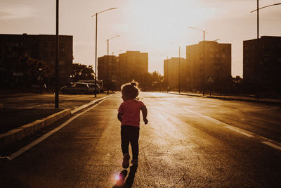 Rear view of girl walking on road in city