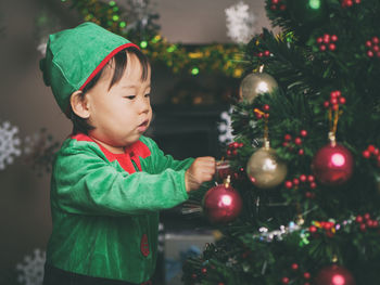 Cute baby girl by christmas tree at home