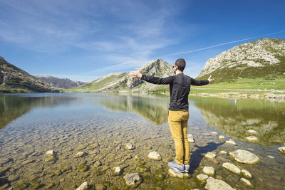 Spain, asturias, picos de europa national park, man standing with raised arms at lakes of covadonga