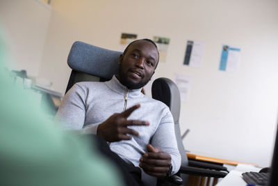 Businessman gesturing while sitting on chair in office
