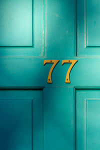 House number 77 on a turquoise wooden front door in london