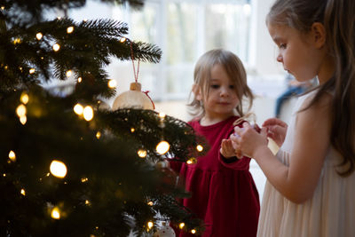 Two little girls decorating a christmas tree together
