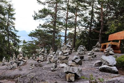 Stack of rocks by trees in forest against sky